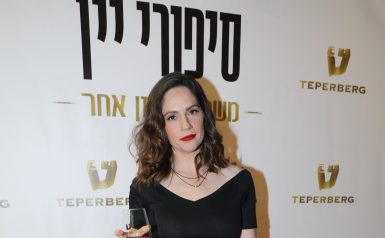 טלי שרון מחזיקה כוס יין על השטיח האדום לוגו טפרברג